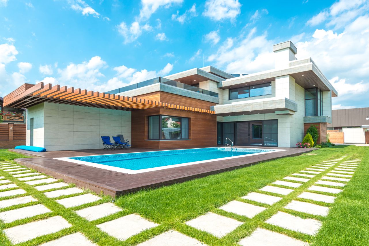 Contemporary house with pool, lush lawn, and clear skies.